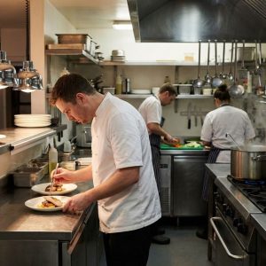 Kitchen staff working collaboratively to prepare food in a busy professional restaurant kitchen.